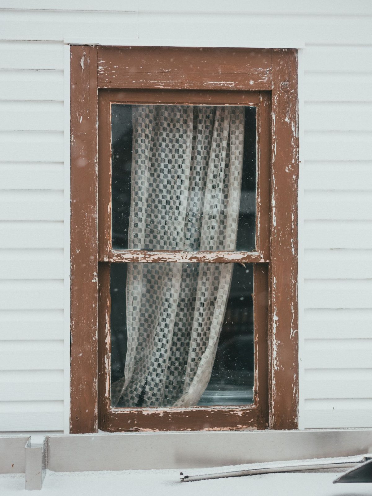 An original timber window with peeling paint and perished putty