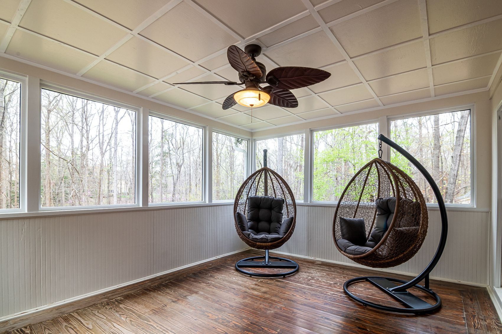A sunroom with windows on three sides looking into the trees