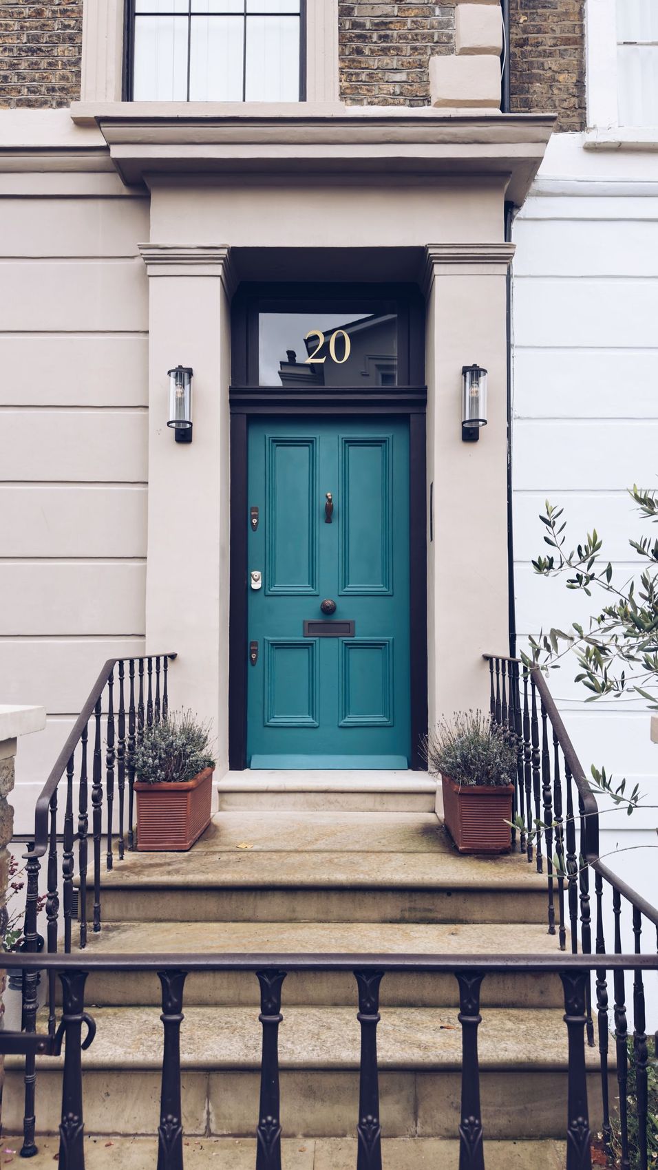 A teal painted front door at the top of stone steps