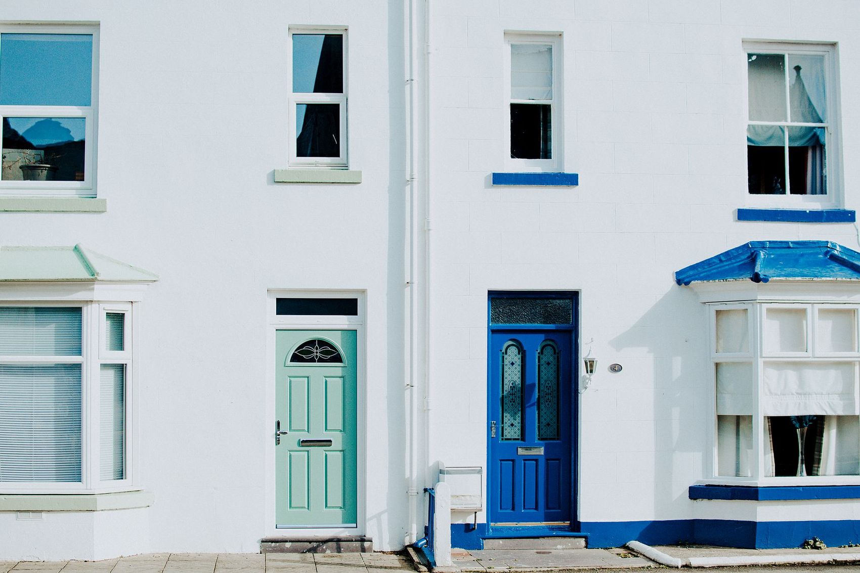 A row of painted front doors on a white-rendered terrace