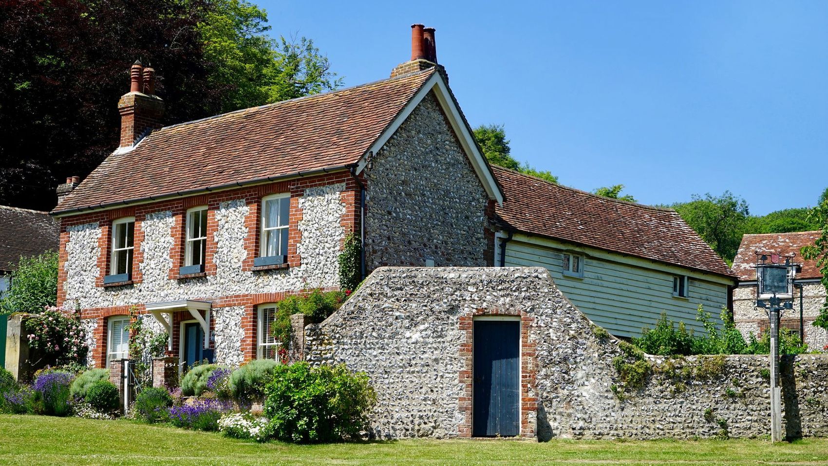A flint and brick cottage with a tiled roof