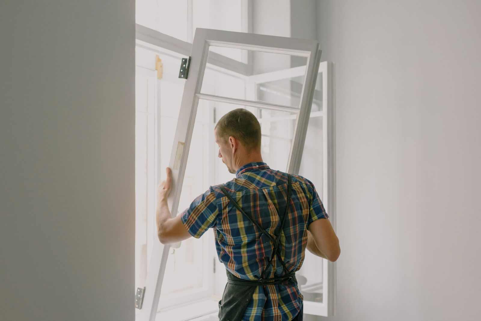 A fitter carrying a new window frame into a property