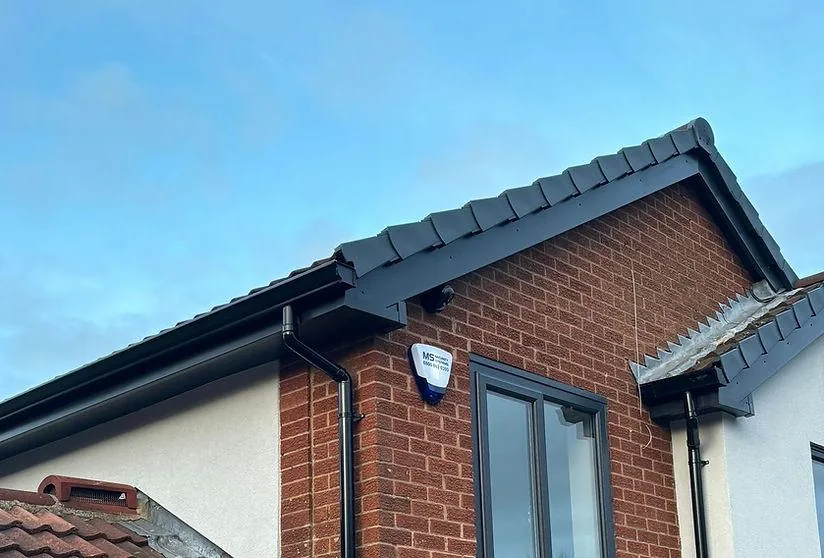 Anthracite fascia and dry verge with black guttering and downpipe on a brick home