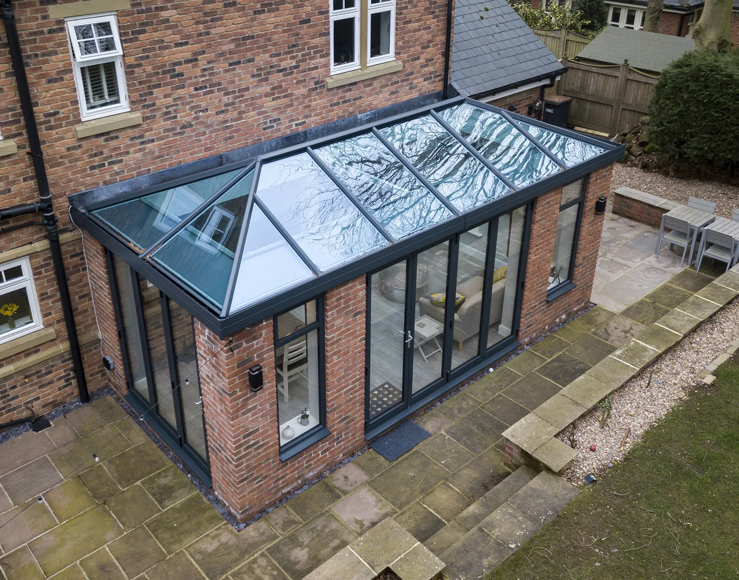 Glass-roof conservatory with anthracite frames and brick pillars