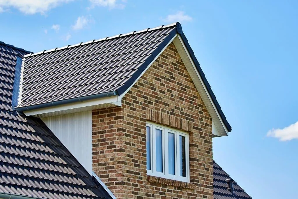 Grey tiled gable roof with dry verge, ridge tiles, soffits and guttering