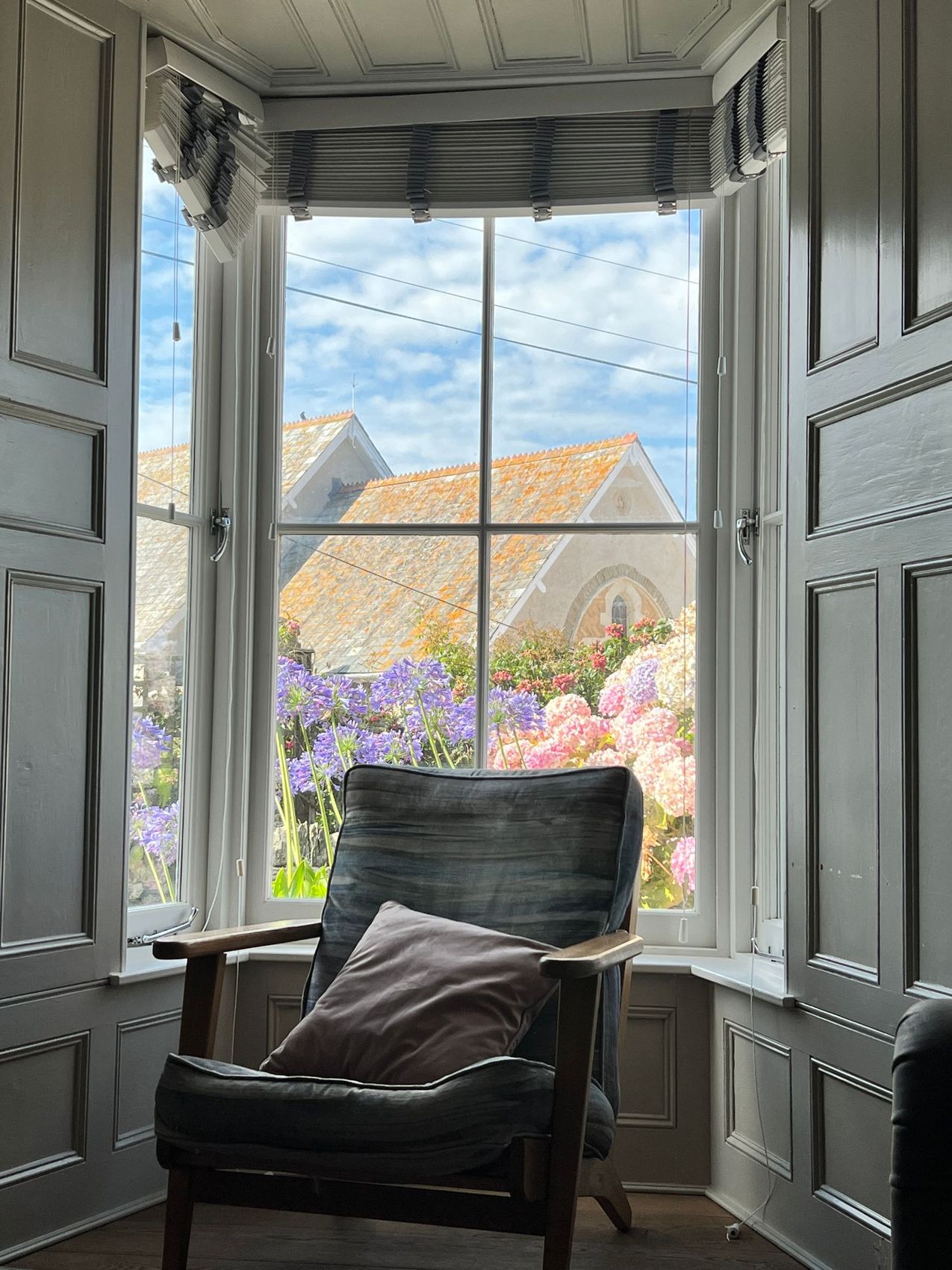 A panelled bay window seat in an English house looking onto the garden