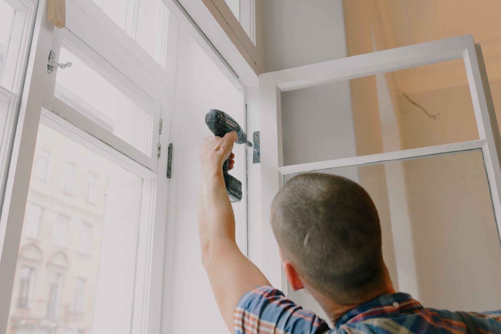 An installer fixing a new window frame into an opening